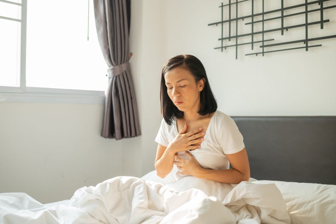 Woman is holding her breasts and not feeling well