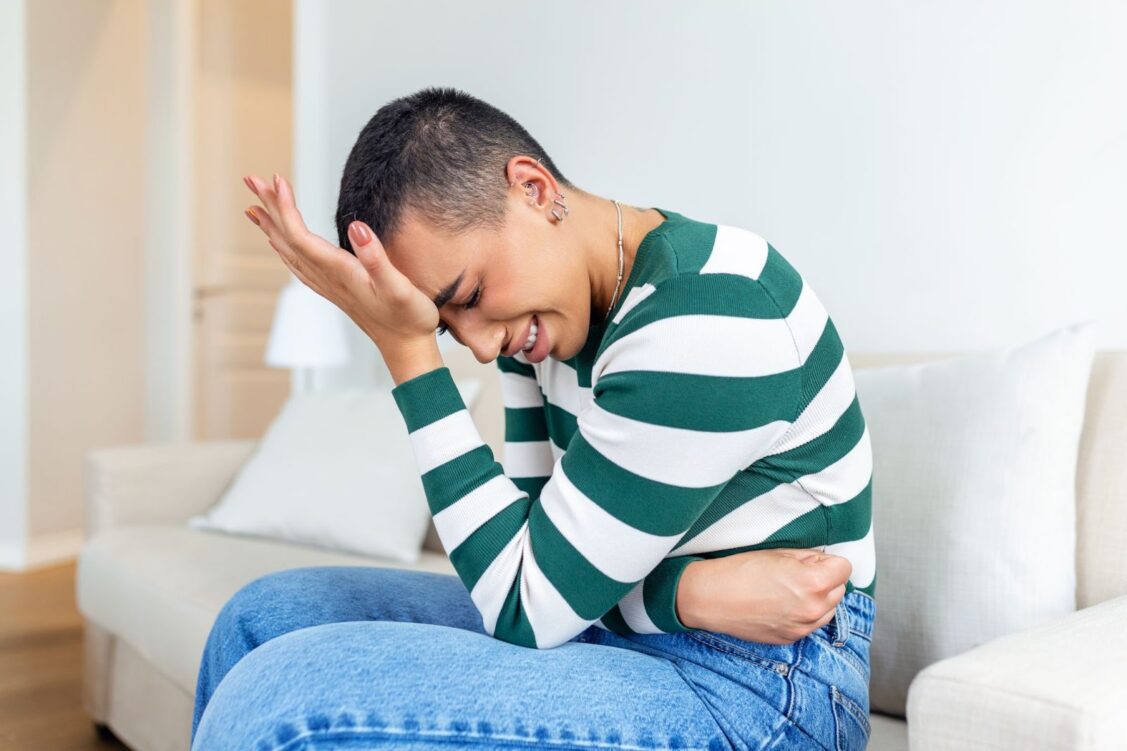 Woman holding hands against belly suffering from pain