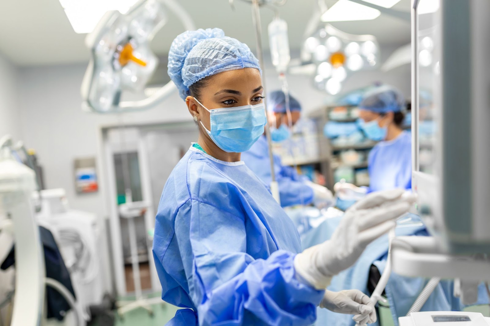 Female doctor in scrubs and a protective face mask preparing an anesthesia machine