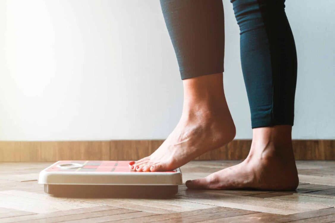 a woman's bare feet next to a floor scale