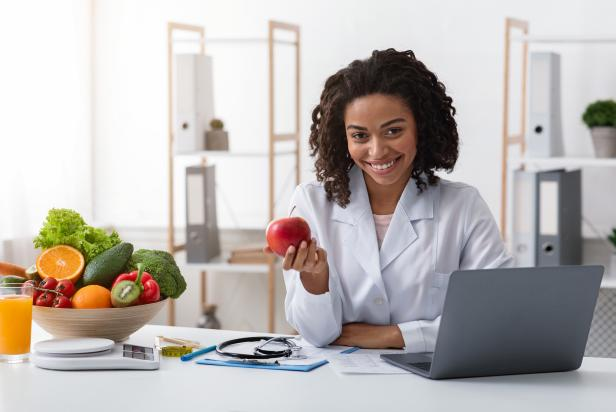 The girl in the white coat is holding an apple