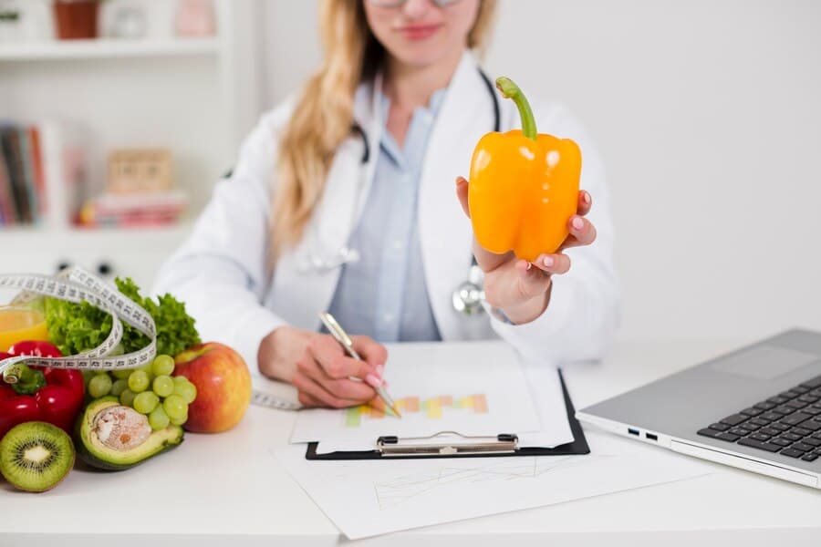 The girl in the white coat holds out the pepper