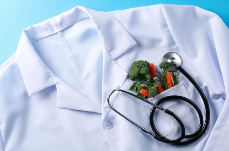 A doctor's coat with vegetables and a stethoscope suggests nutritional health